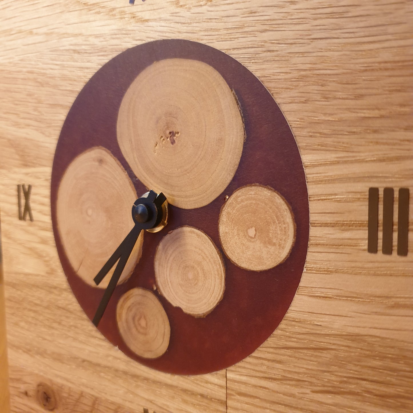Uhr aus massivem Eichenholz mit Inlay aus kleinen Baumscheiben, eingefasst in weinroten Kunstharz. Leises, geräuscharmen, lautloses Quarzuhrwerk